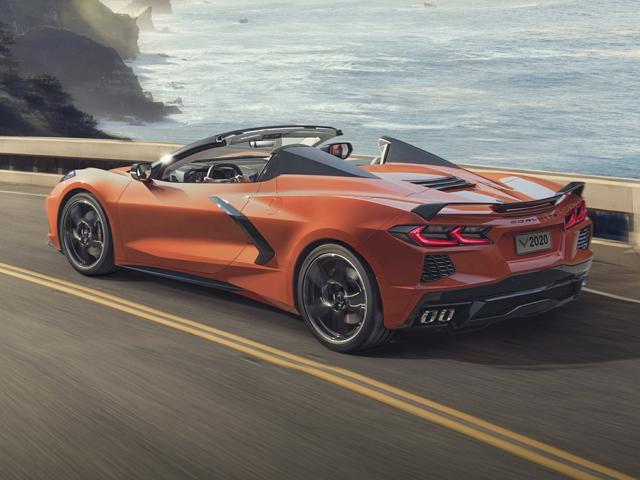 2024 Orange Chevy Corvette cruising along an oceanside highway.