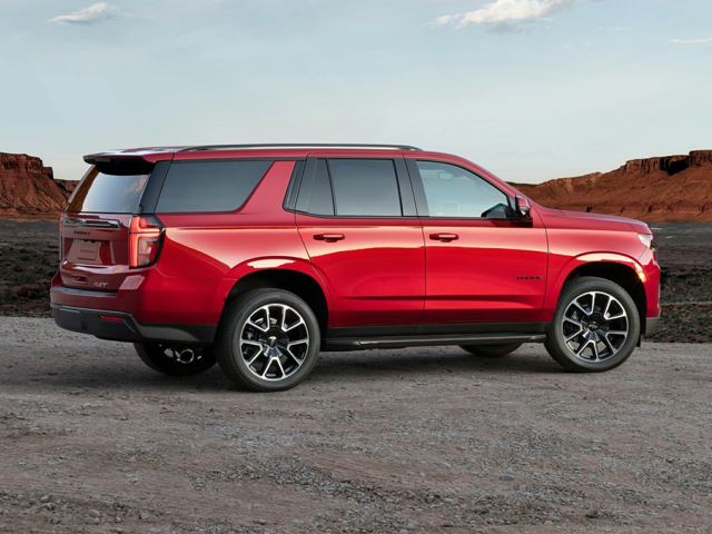 An All-New 2024 Radiant Red Tintcoat Chevy Tahoe parked on a gravel road in front of a beautiful backdrop of mountain plains.